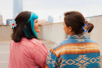 Two women with star shaped quilt clips standing on a rooftop with city skyline in the background