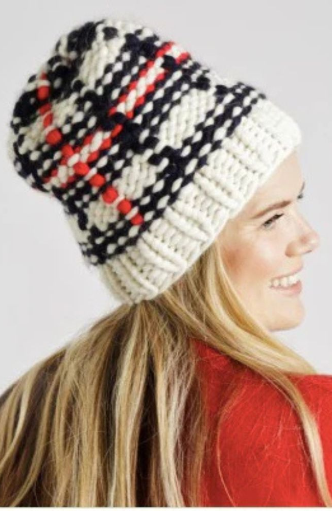 Blonde woman in red shirt wearing a black, white, and red plaid beanie.