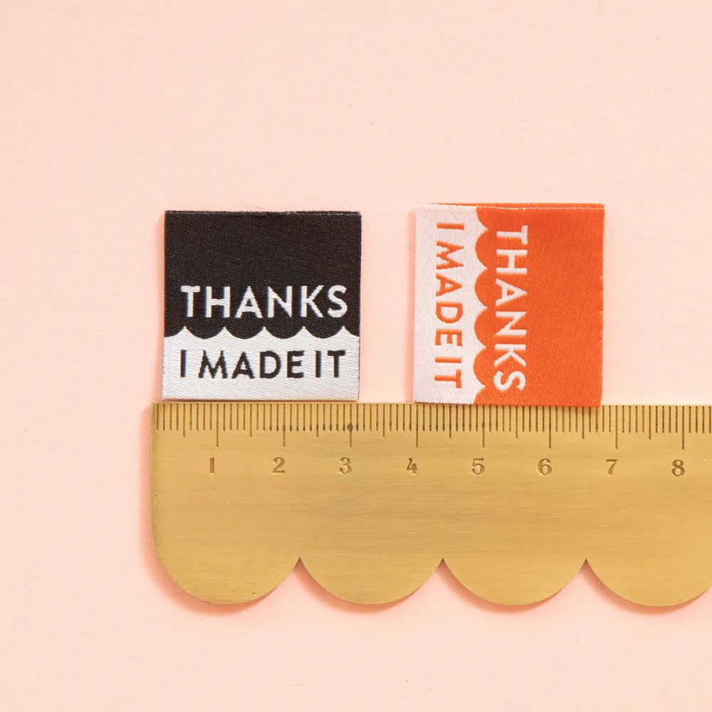 Two small rectangular stickers with 'Thanks I Made It' text on a pink background, with a gold ruler for scale.