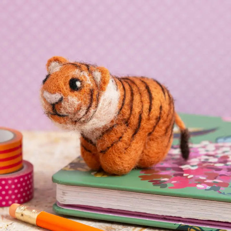 Small felt tiger on a colorful book with a purple background