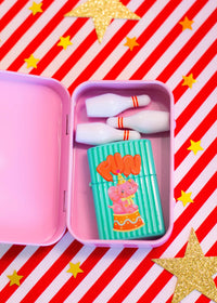 Pink container with a cartoon character lighter on a red and white striped background with gold stars.
