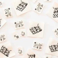 Labels with designs including "Quilter," a matchstick box and a chicken scattered against a white background. 