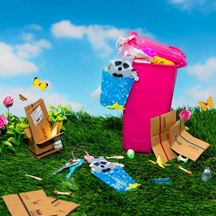 Keychain of a raccoon in a trash can hanging from a pink trash can in nature