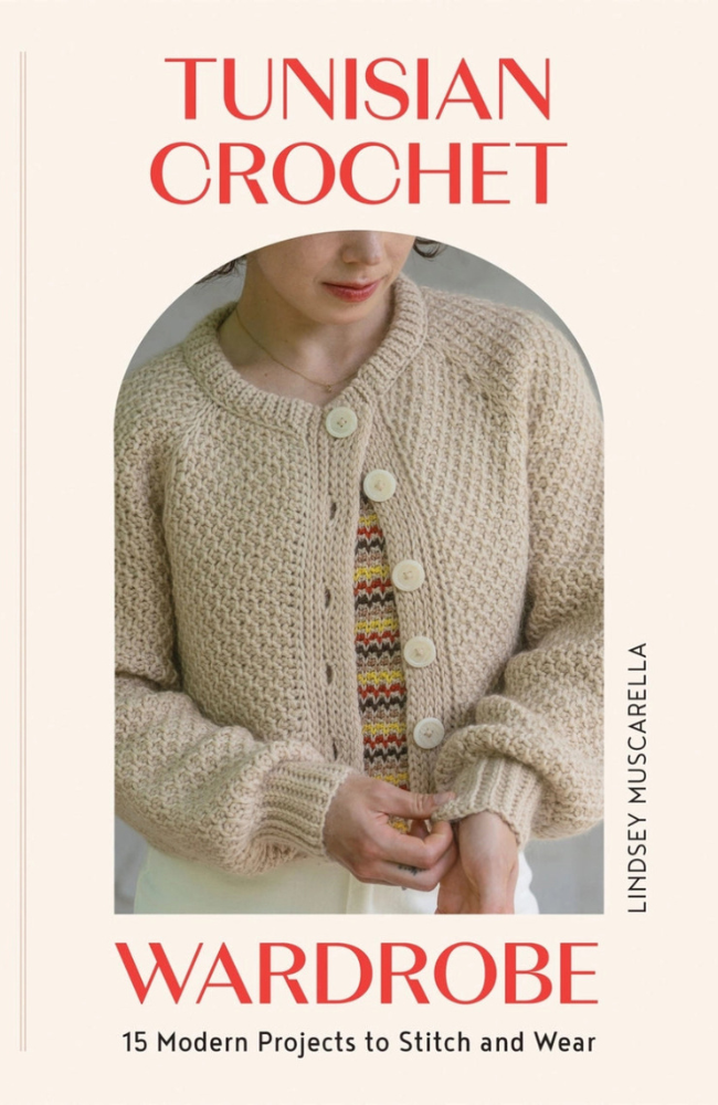 Woman in a white tunisian crocheted sweater with a patterned shirt underneath on a cream background with red writing stating "Tunisian Crochet Wardrobe"