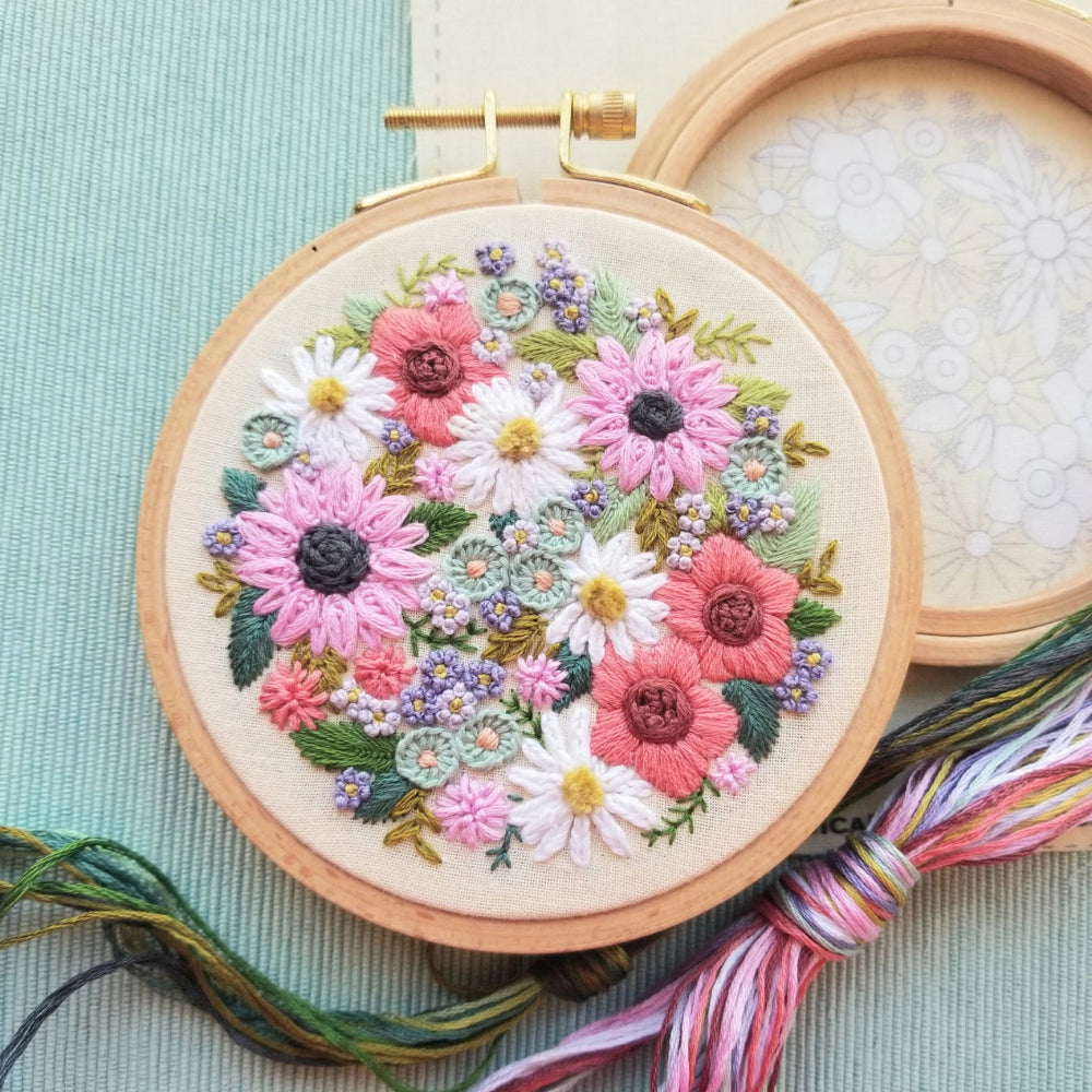 The Wildflower Sampler Embroidery Kit by Jessica Long Embroidery, with a hoop containing a stitched design of many pastel flowers
