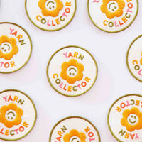 Multiple circular fabric patches with a smiley face flower and text reading "Yarn Collector" on a white background.