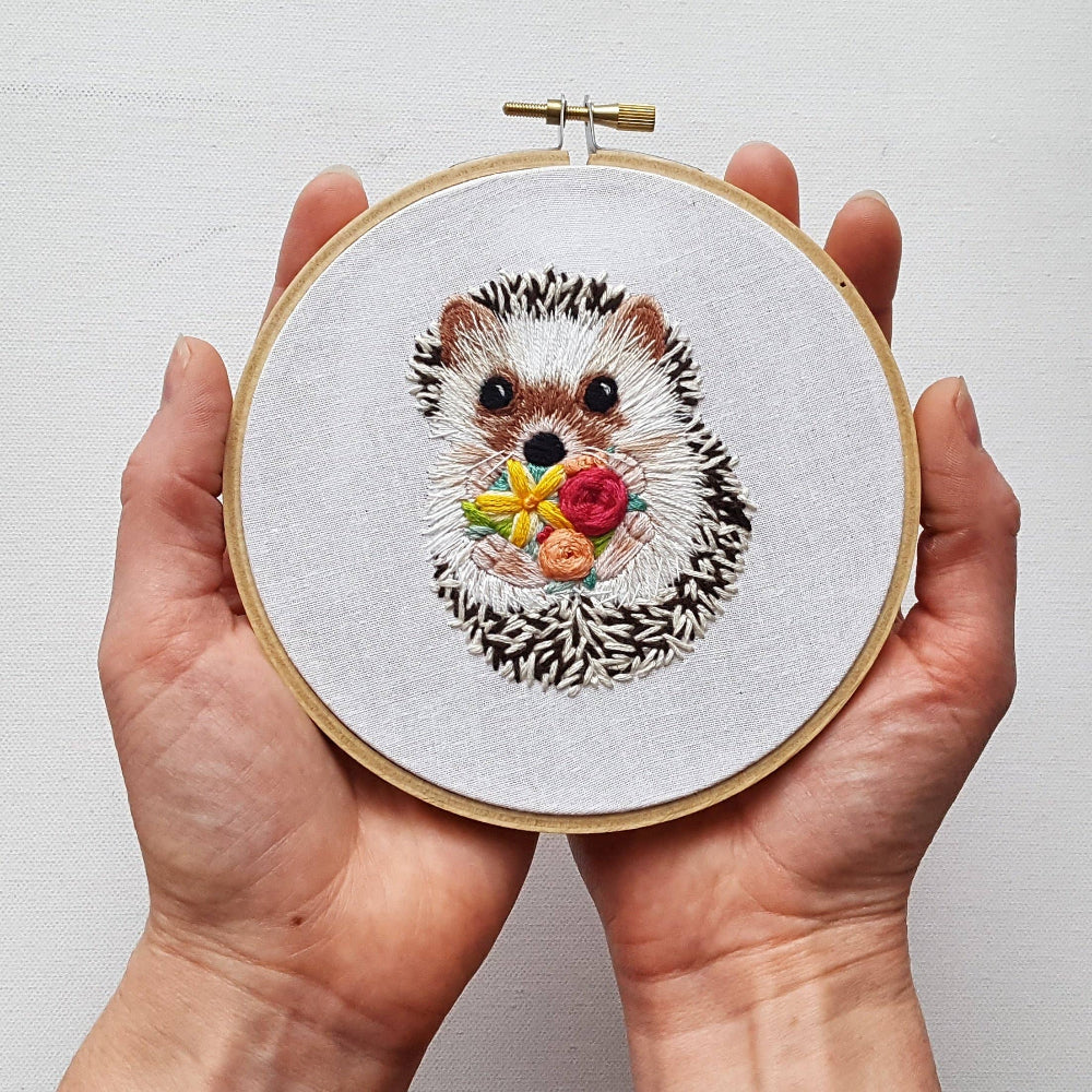 Hedgehog Embroidery Kit by Jessica Long Embroidery: an embroidery hoop with a small hedgehog holding flowers